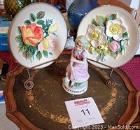 Two vintage W.H. Bossons handpainted chalk-ware wall plates with floral designs and a small figurine of a girl, displayed on a decorative tray showing all items together.