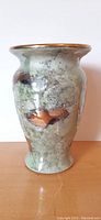Front view of sage green studio pottery vase showing iridescent and gold accent details