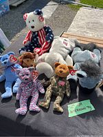 American-themed Beanie Babies and Buddies collection displayed outdoors on a black surface. Includes various patriotic bears and political figure plush toys, all with TY tags.