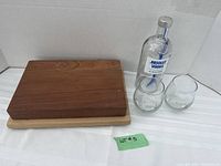 Full set showing butcher's block cutting board, two Absolut Vodka collector glasses, and collectible bottle