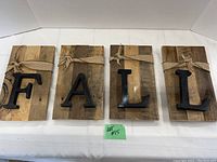 Front view of four wooden boards spelling FALL with black metal letters and burlap ribbons