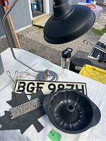 Photo showing the office lamp, license plate, cheese plate with attached sign, Bundt cake pan and water bottle on white tablecloth outdoors.