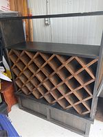 Front angled view of the handmade wooden wine rack showing dark finish, lattice compartments for bottles, and sizeable counter shelf on top.