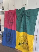 Full shot of fabric shower curtain showing four Hogwarts house crests in distinct colors