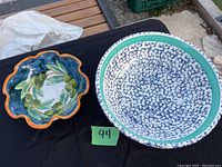 Two ceramic bowls on display: the described fruit bowl with olive and leaf design in blue and orange scalloped rim, and a second not included item with a white and blue crackle pattern and green rim.