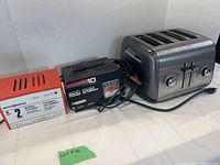 Photo showing the KitchenAid 4-slice toaster, Motomaster 2 amp battery charger, and Schumacher 10 amp battery charger side by side.