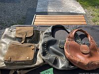 Two Matt & Nat leather bags (one black, one brown) and one Aldo leather backpack displayed on a dark fabric surface outdoors, showing their overall size and condition.