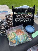 Bracelets rolled and displayed on three black velvet stands, with some stacked beside stands and a sealed plastic bag of decorative gift bags near them.