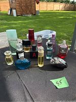 Photo of 12 perfume bottles outdoors on table with grass and fence background
