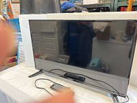 RCA LED TV displayed from front on a table with power cord and remote in front.