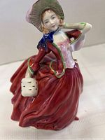 Side view of Royal Doulton Autumn Breezes figurine showing pink corset, blue scarf, and small handbag