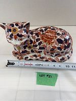 Front view of the detailed vintage Japanese Imari cat figurine with visible floral pattern and measuring tape showing 11 inch length.