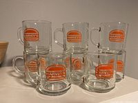 Group of 8 Harveys glass mugs stacked and arranged showing the orange Harveys logo on each mug.