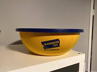 Side view of the yellow plastic mixing bowl with Blockbuster Video logo and blue lid