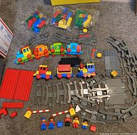 Overview of the train cars, track pieces, figures, and accessories laid out on floor showing full quantity and variety.