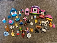 Overview of all Lego Duplo pieces including Disney characters, animals, and building blocks arranged together on carpet.