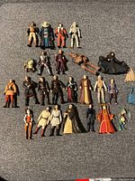 Array of 24 Star Wars action figures arranged on grey fabric background.
