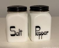 Front view of the vintage milk glass salt and pepper shakers showing clear 'Salt' and 'Pepper' labels.