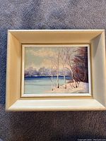 Full view of original oil painting in cream-colored frame showing winter landscape with birch trees and water