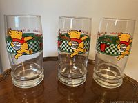 Three Winnie the Pooh drinking glasses side by side showing front designs with Pooh holding a honey pot