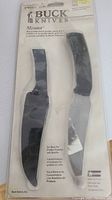 Photo of sealed retail packaging front showing Buck Knives Mentor fixed blade knife with thermoplastic sheath, black color.