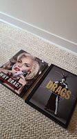 Two coffee table books placed on carpet floor side by side, showing overall items for sale