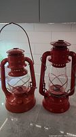 Photo showing the two vintage kerosene lamps side by side, orange No2 D-Lite and red No.123 Crescent Dietz lamps.