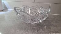 Side angle view of antique pressed glass bowl showing intricate pattern and sawtooth edge.
