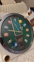 Close-up photo of Panclox billiards-themed quartz wall clock, showing numbered billiard balls as hour markers and branding.
