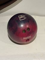 Bowling ball showing side with 'B' logo and finger holes, purple-pink swirled color pattern