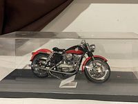 Side front view of the 1957 Harley Davidson XL Sportster scale model inside its clear plastic display case, showing detailed paint and chrome accents.