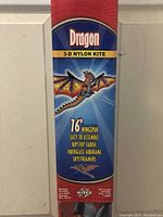 Close-up photo of the kite packaging showing brand, product name, and specs including 76 inches wingspan, fiberglass airframe, ripstop fabric and sky streamers.