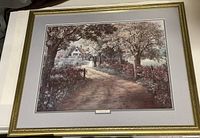 Framed art print showing the scenic depiction of a tree-lined country lane leading to a cottage.