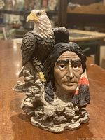 Front view of the mini statue showing the American Indian male figure with eagle prominently on the shoulder, detailed facial features, feather detail, and rocky base.