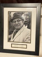 Framed black and white photo of Vince Lombardi with White mat and plaque below the photo indicating Green Bay Packers.