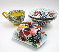 Four ceramic items: a butter dish with lid, one tea cup, and two bowls all with colorful floral designs.