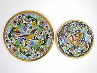 Lot includes two decorative ceramic plates from Spain by Ceramics Sevilla, one large 10.5-inch diameter with floral multi-color design and gold-tone trim, one smaller 8-inch with deer motif and gold-tone trim