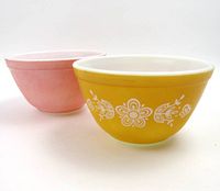 Photo shows two mixing bowls side by side, pink matte bowl on the left and yellow matte bowl with white floral pattern on the right.