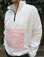 Front view of the white nylon windbreaker jacket, showing pink front pocket with smiley face and elastic cuffs.