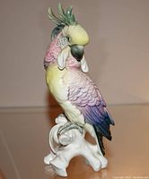 Front three-quarter view showing pastel pink, yellow, lavender body and green crest