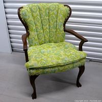 Three-quarter front left view of armchair showing overall shape, upholstery and carved legs