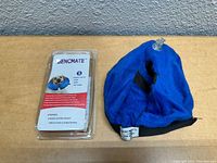 Photo showing the Bencmate inflatable collar inflated and next to its packaging on a wooden surface against a gray wall.