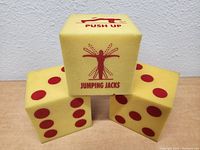 Three yellow foam dice showing red dots and exercise instructions such as 'Push Up' and 'Jumping Jacks'.