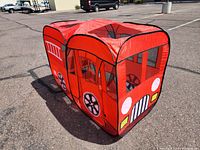 Red pop-up play tent with fire engine design viewed from front and side, showing black and white wheel graphics, grille, and ladder print on the sides.