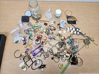 Full display of diverse costume jewelry pieces including necklaces, bracelets, earrings, brooches, and pins spread out on a table.