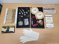 Overview of assorted small items on table including chains, plates, pins, gloves, wallet, and lanyard