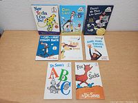 Full view of all eight books arranged on a wooden surface, showing the cover of each book.