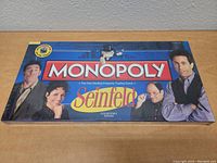 Top-down photo of the sealed Monopoly Seinfeld Collector's Edition box showing the main characters from the TV series.