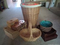Wide shot of collection showing large laundry basket, small oval basket, two hand-painted wooden boxes, wooden tray with woven bowl, and light wooden box