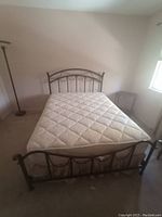Front view of assembled metal bed frame with mattress against wall